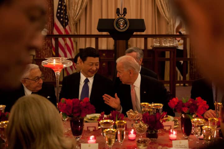 Kinas president Xi Jinping och dåvarande vice president Joe Biden konverserar vid ett bord med mat och andra gäster, inklusive Henry Kissinger.