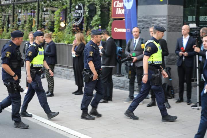 Fyra poliser går förbi reportrar på väg in i en valvaka.