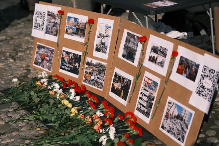 An array of flowers lie in front of a gallery of pictures from the earthquake in Turkey.