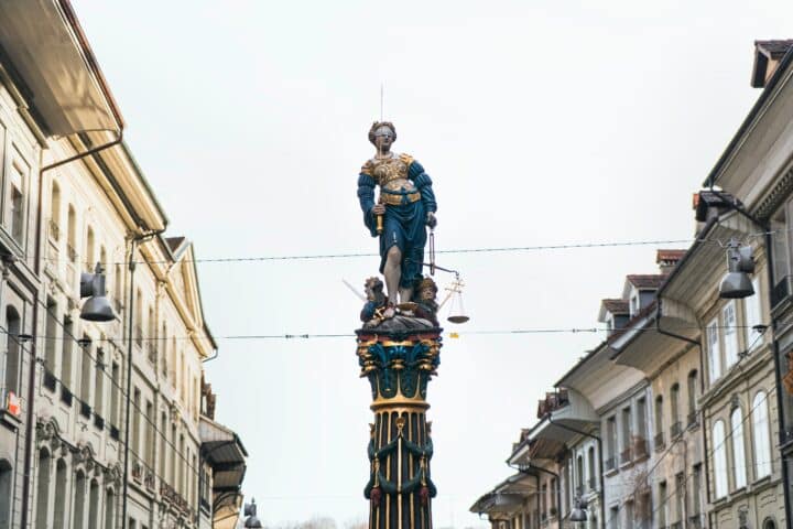 A statue atop a column, blinded and holding scales, representing justice. In Bern, Switzerland.