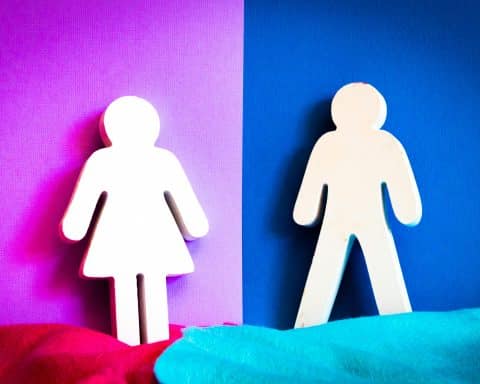 A cutout of a woman, leaning on a pink wall, and a cutout of a man, leaning on a blue wall.