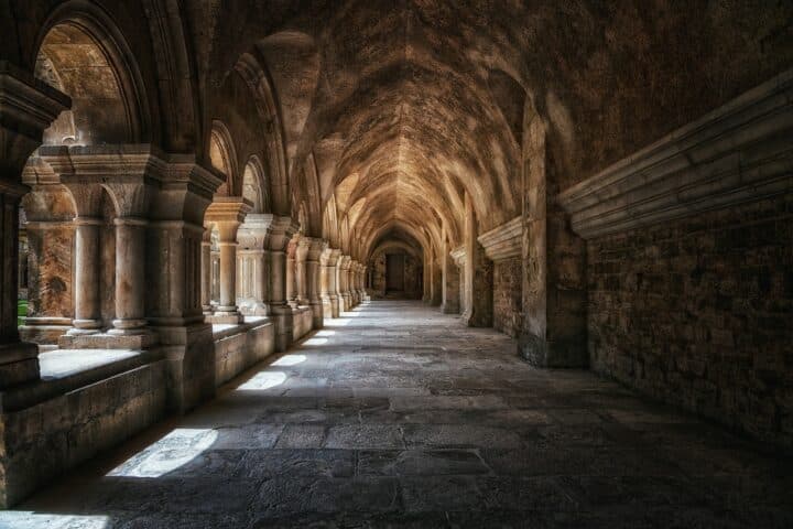 A dark vaulted passage in an old monastery.
