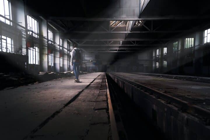 A person walking through a dark, abandoned warehouse.