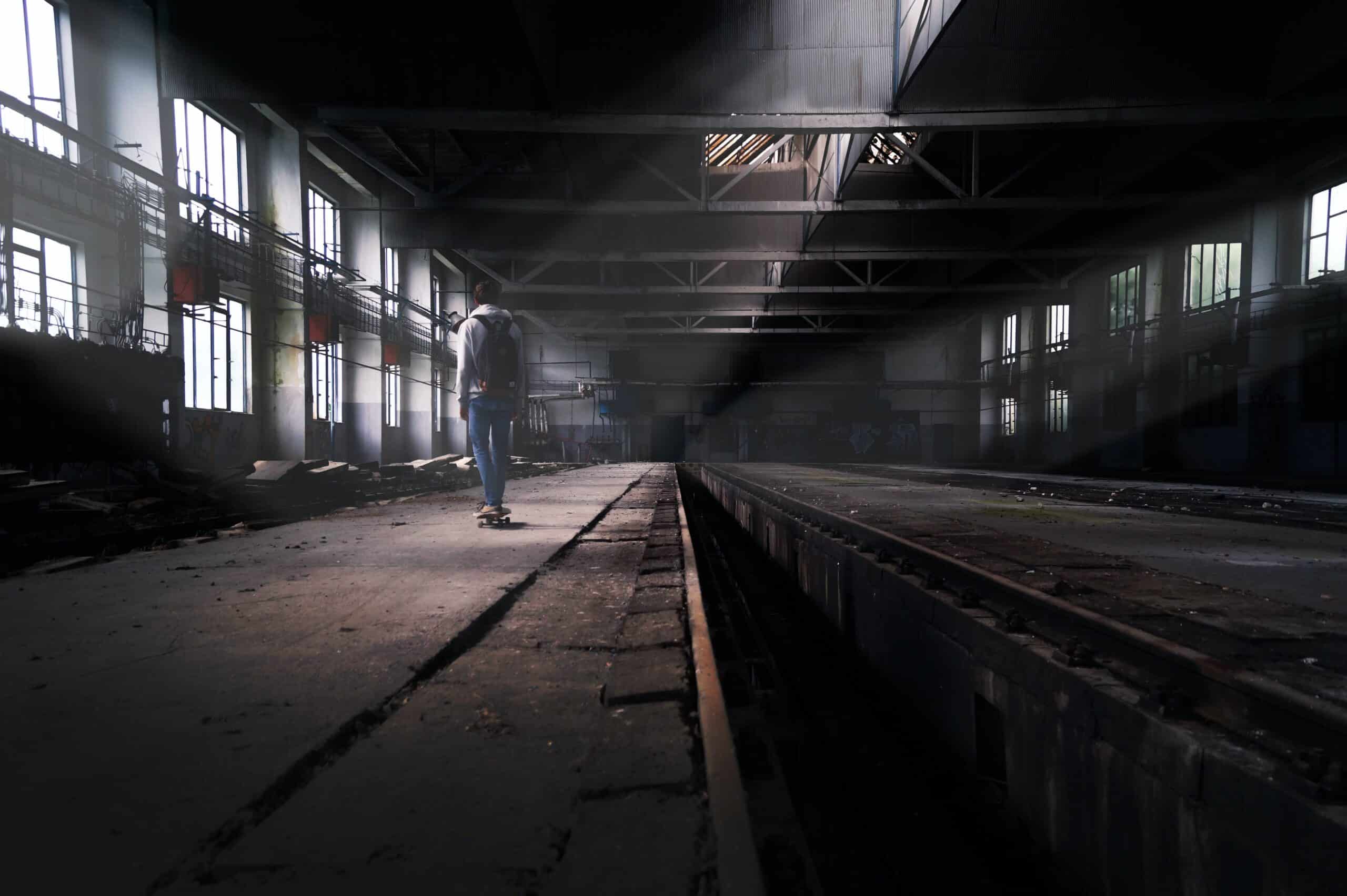 A person walking through a dark, abandoned warehouse.