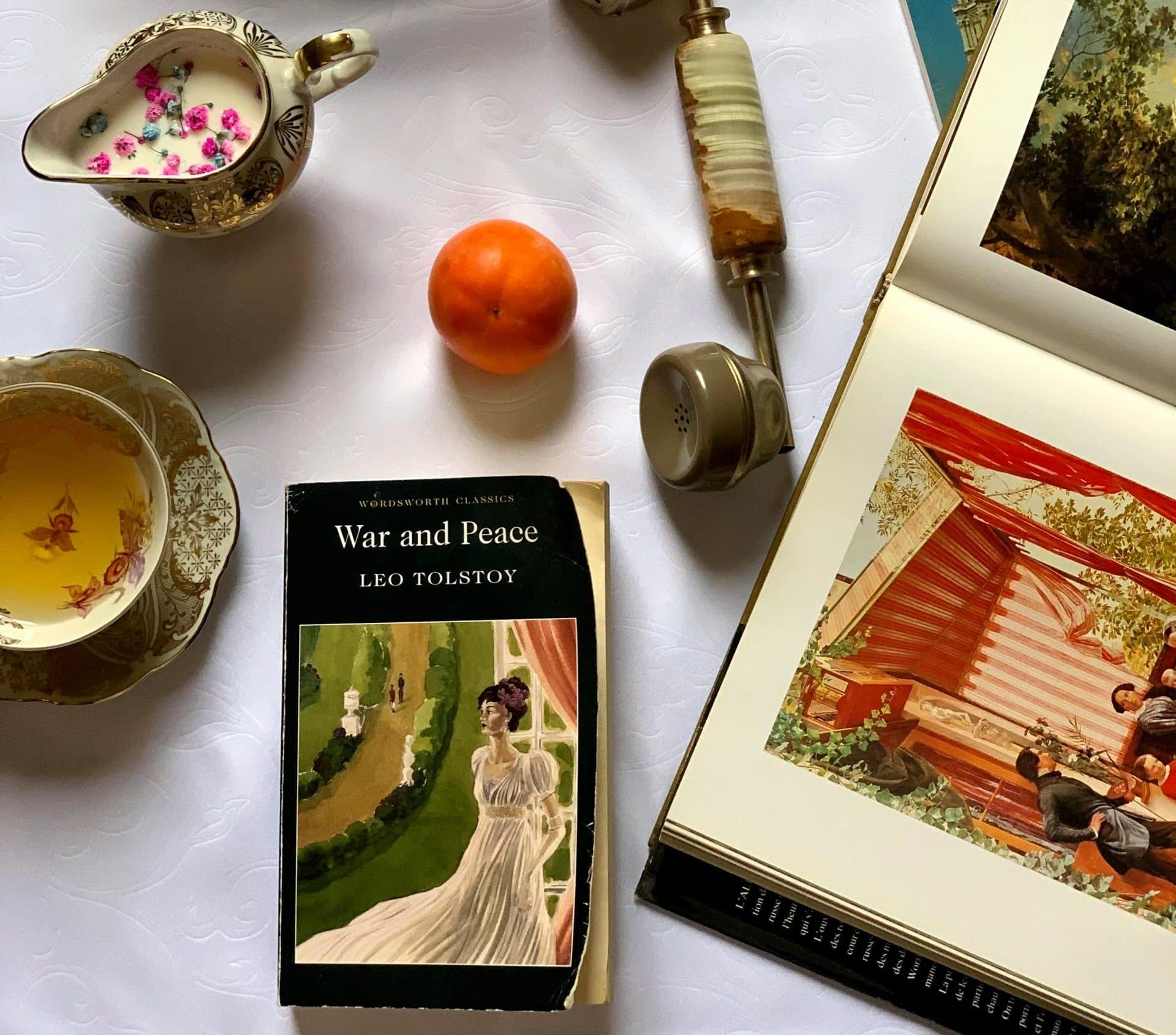 Antique items on a white table, including the book "War and Peace" by Leo Tolstoy.