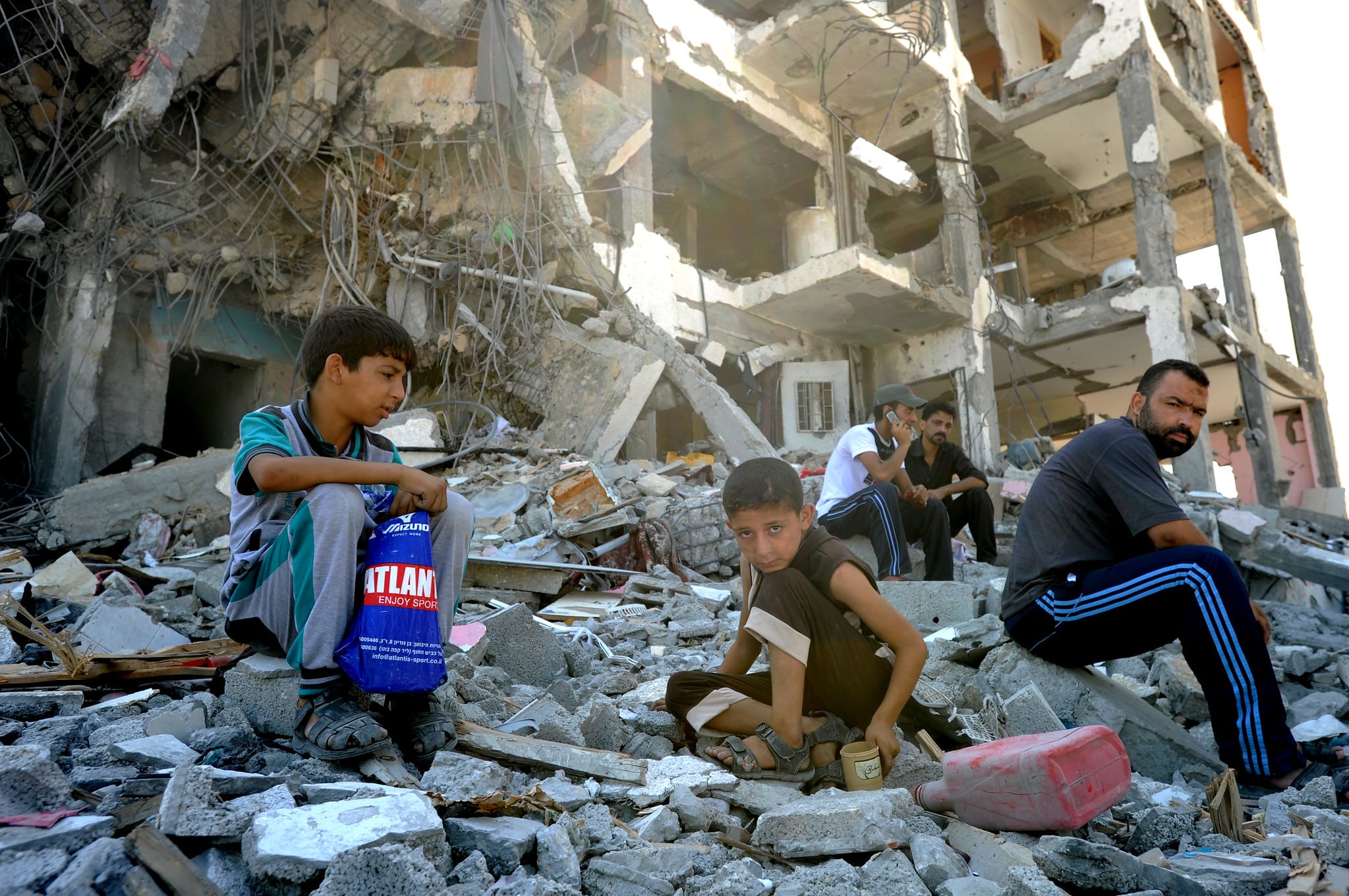 A group of Palestinians, including children, are searching through the rubble of a destroyed building in Gaza.