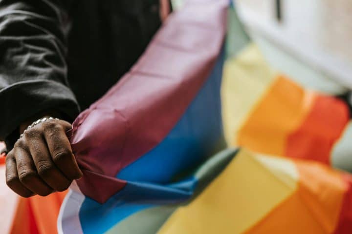 Person holding an LGBT flag in their hands.