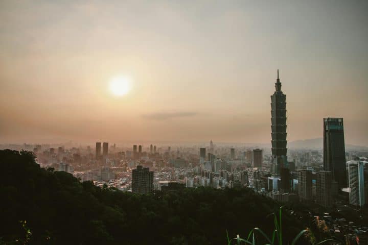 A view of Taipei, capital of Taiwan, from the top of a mountain. The sun is rising over the skyscrapers.