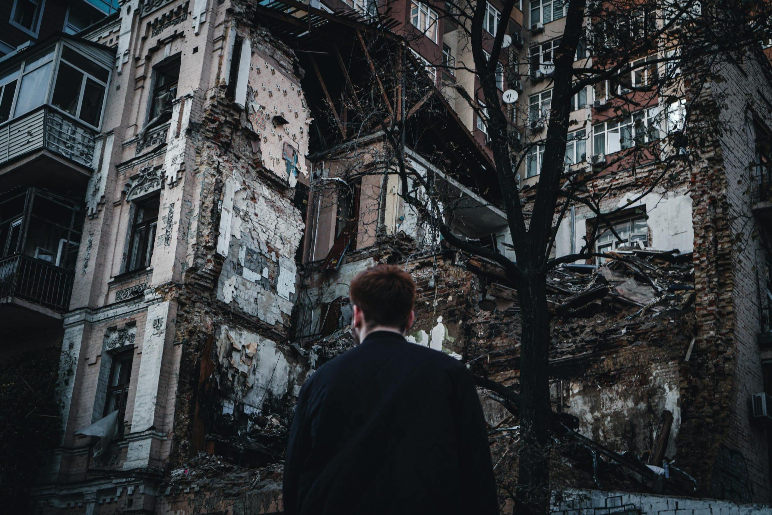 A man looking up at a partially destroyed apartment building which has been struck by a bomb, in Kyiv, Ukraine.