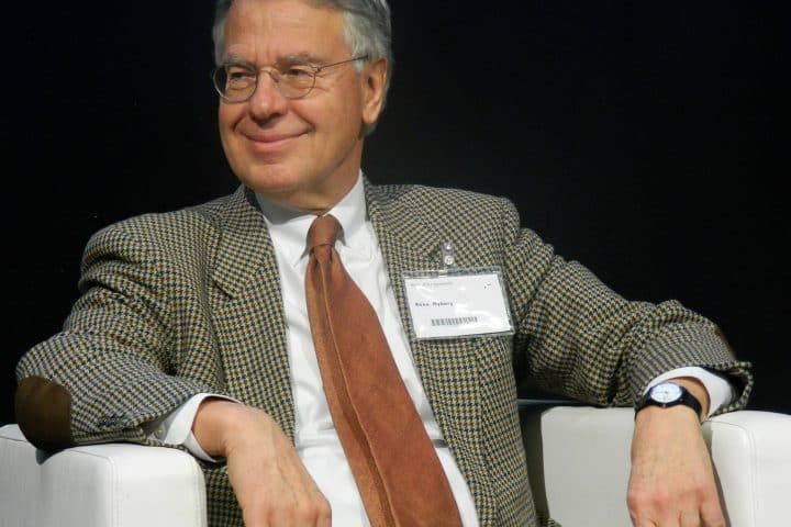 Ambassador René Nyberg, dressed in a suit with an orange tie, sits and smiles in an armchair while speaking at the Helsinki bookfair in 2017.