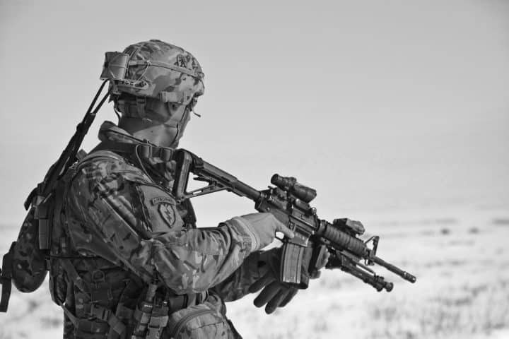 Soldier scouting the landscape, rifle in hand.