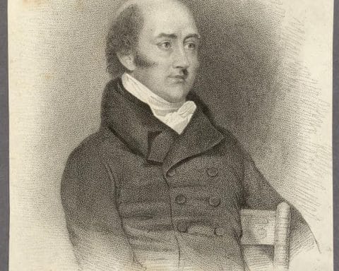A portrait of George Canning when he was an Member of Parliament. He wears a dark coat with buttons and is sitting in a chair.