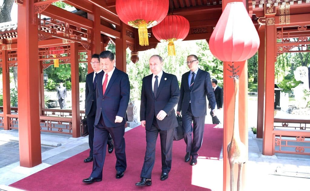 Chinese President Xi Jinping and Russian President Vladimir Putin walk together underneath a traditional Chinese pavilion. The meeting took place in the Belt and Road forum, 2017, during which the New Silk Road was extensively discussed.
