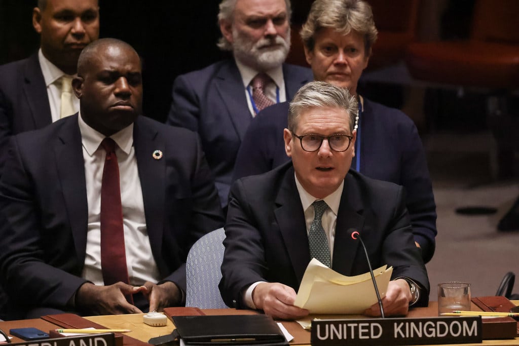British Prime Minister Keir Starmer speaking at the U.N. with a sign reading "UNITED KINGDOM" in front of him. Behind him sits Foreign Secretary David Lammy.