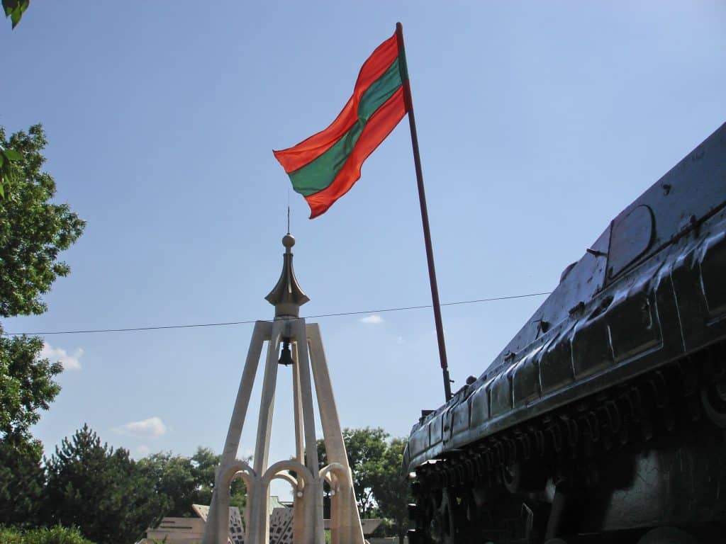 The Transnistrian flag waving from a tank in front of a war memorial.
