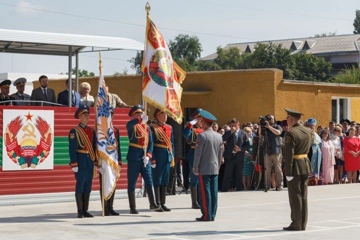 Soldiers performing a ceremony, saluting the Transnistrian flag.