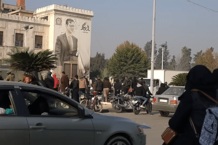 A wall with the imagery of Assad has been riddled with bullets.
