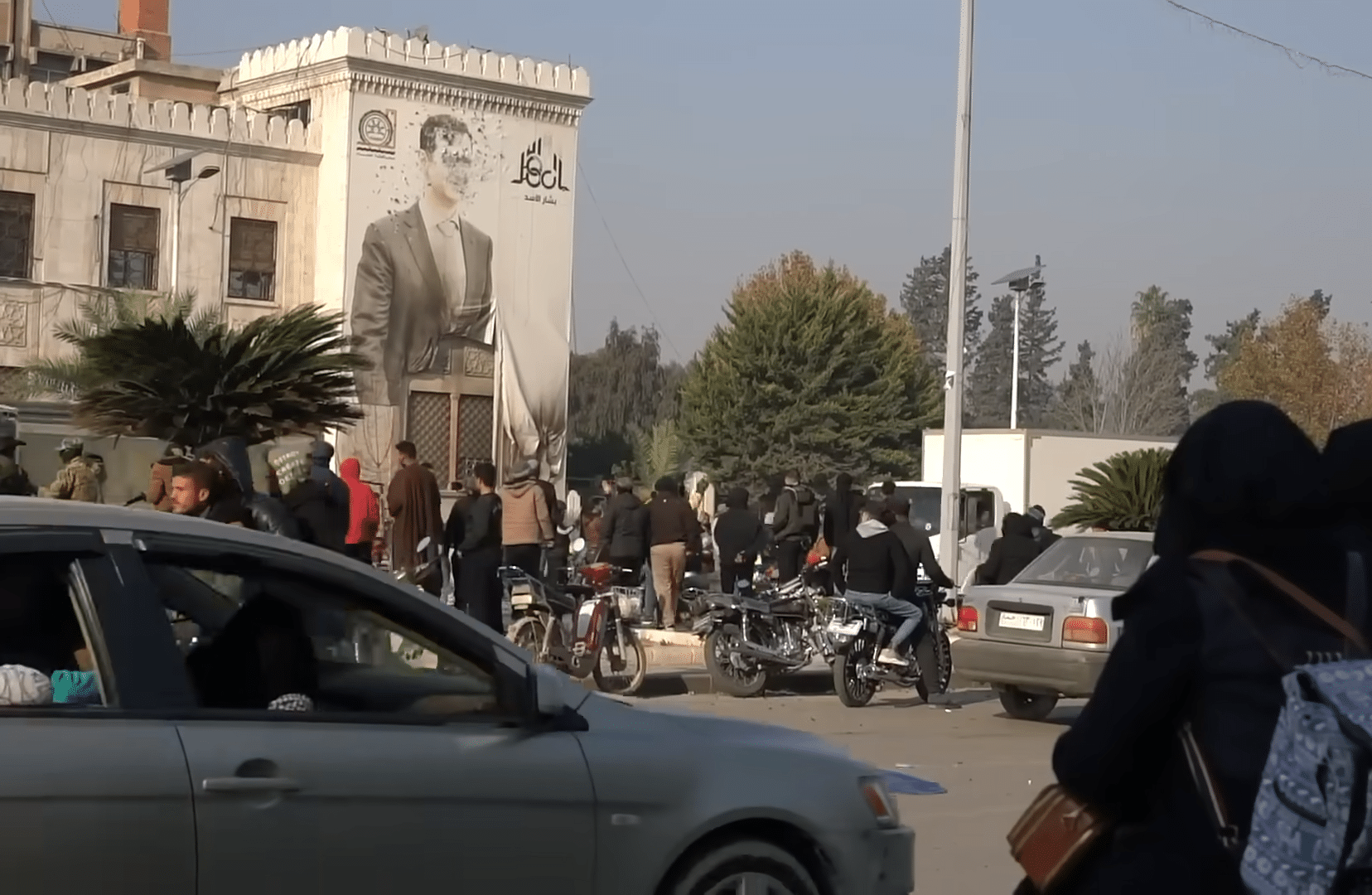 A wall with the imagery of Assad has been riddled with bullets.