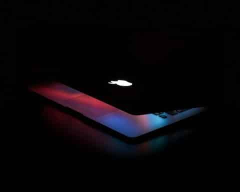 A MacBook closing, its light fading.